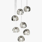 Seven rotating crystal LED pendant lights with abstract glass forms, modern chandelier by Maison Ornate.