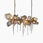 Modern Nordic chandelier with smoky irregular glass, metallic spikes, and twin chains; emits warm light.