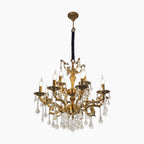 Ornate gold multi-arm chandelier with eight candle lights, crystal prisms, and dark wrapped chain.