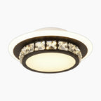 Modern chandelier with black circular ring, square crystal accents, and frosted diffuser emitting warm light.