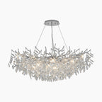 Polished aluminum chandelier with crystal leaf branches, suspended by four wires, emits elegant LED light.