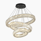 Three crystal-adorned rings form a modern chandelier, suspended from a sleek black ceiling mount.