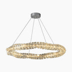 Modern chandelier with twisted translucent LED crystal ring, suspended by four wires from metal base.