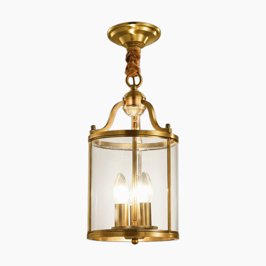 Modern gold chandelier with cylindrical glass shade, three candle bulbs, brass canopy, and twisted brown rope.