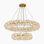 Gold-tone chandelier with dual rings, clear leaf-shaped crystals, and floral accents, elegantly suspended.