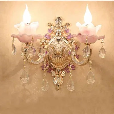 Ornate Art Deco chandelier with two candle bulbs, pink floral glass shades, gold trim, and crystal pendants.