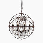 Ornate American industrial chandelier with candle lights, crystal pendants, in a spherical birdcage iron frame.