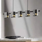 Five tinted cylindrical glass shades on a black bar create a modern Scandinavian hallway chandelier.