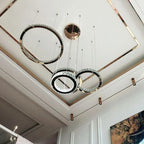 Modern chandelier with three gold-accented, crystal-edged steel pendants at varied heights.