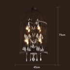 Art Deco chandelier with a black iron birdcage frame, dangling crystals, and glowing bulbs.