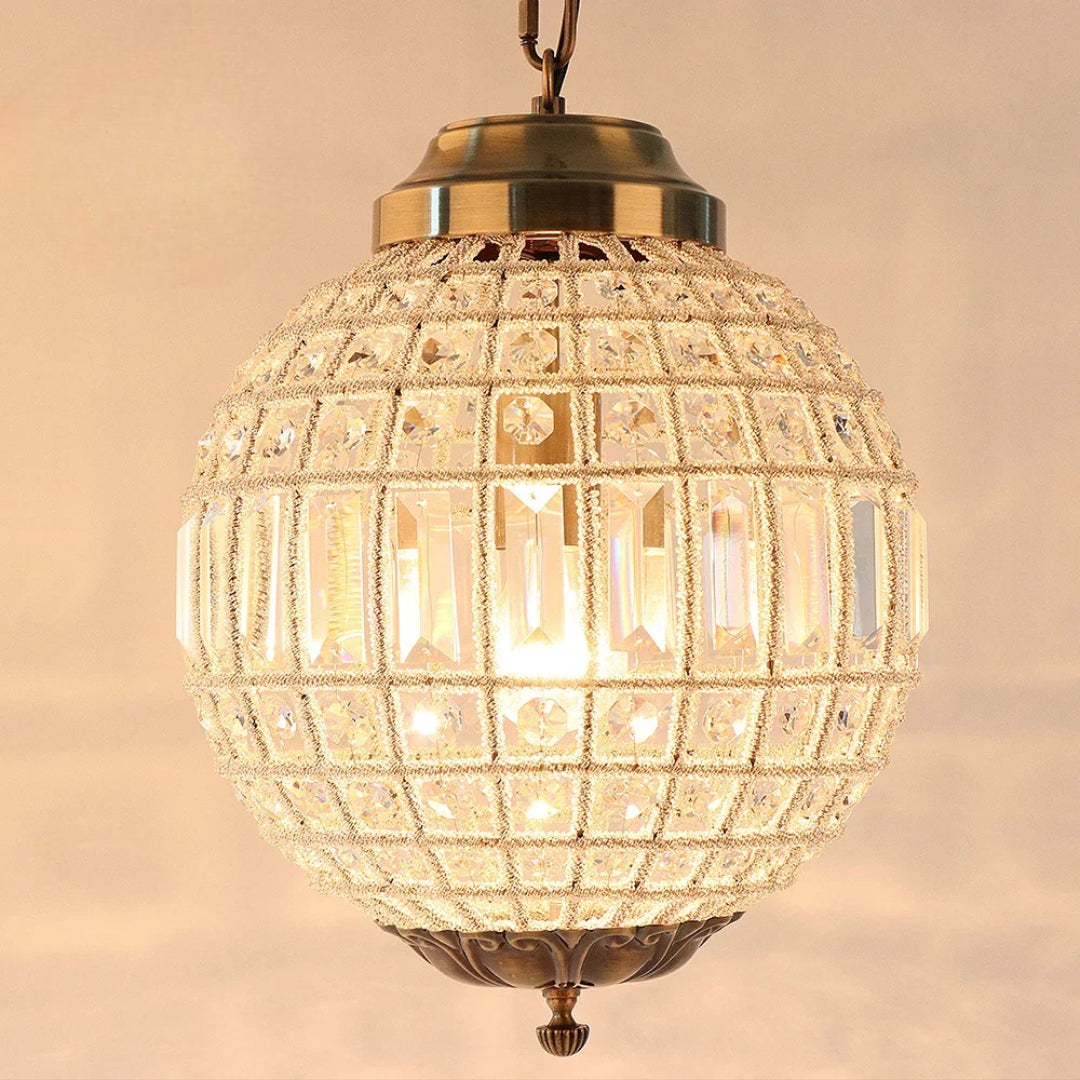 Gold-toned Empire-style crystal glass chandelier with geometric patterns, glowing warmly from internal LED lights.