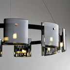Elegant Scandinavian chandelier with curved smoked glass panels and warm LED bulbs suspended by thin wires.