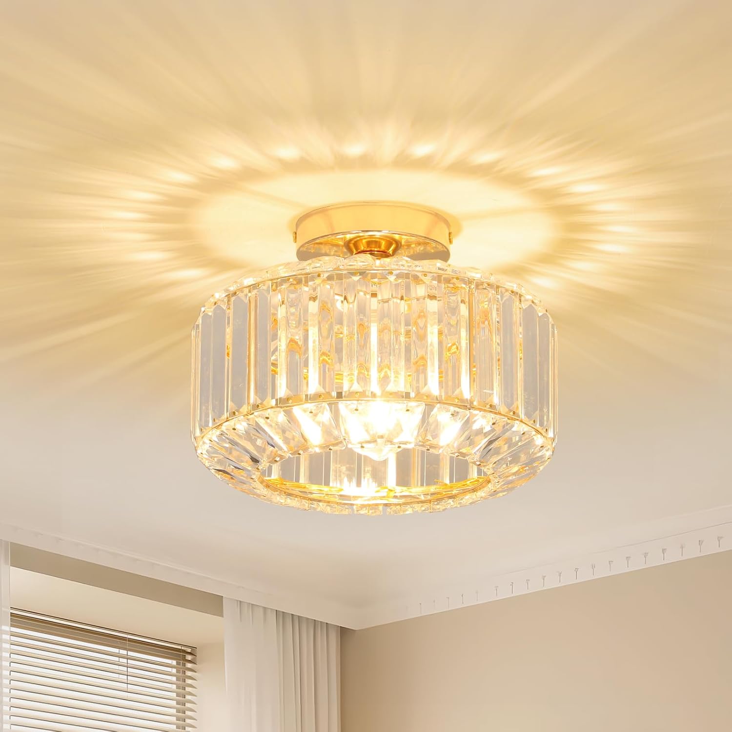 Modern crystal chandelier with gold base, vertical rods, glass shade; creates starburst light effect.