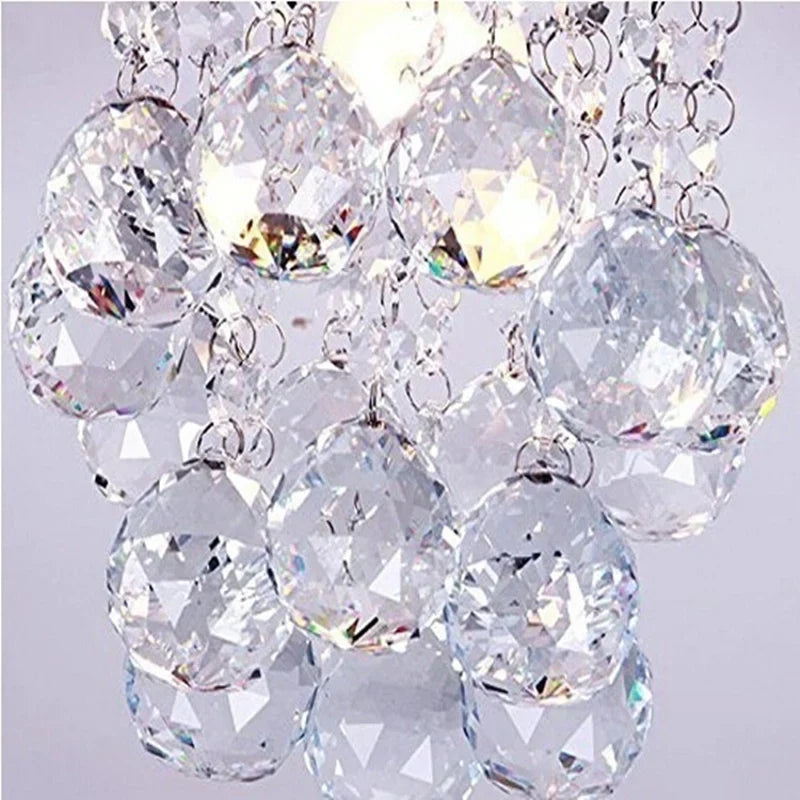 Close-up of crystal pendant chandelier with silver chains and tassels, shimmering with refracted light.