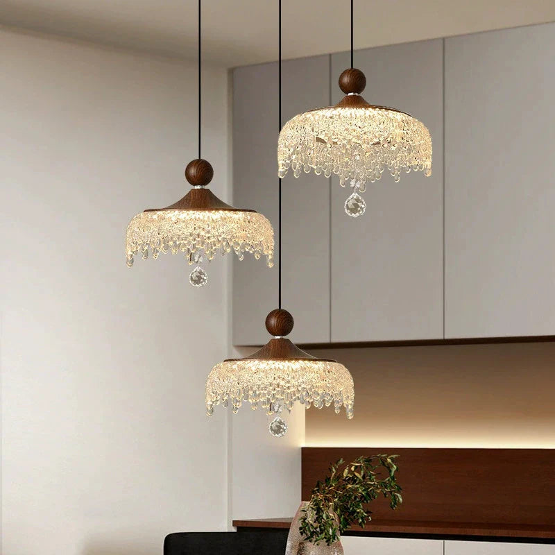 Three ornate French medieval-style crystal teardrop chandeliers with wooden tops and crystal beaded fringe.