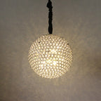 Maison Ornate Round Crystal Ball LED chandelier, suspended and emitting warm glow with intricate light patterns.