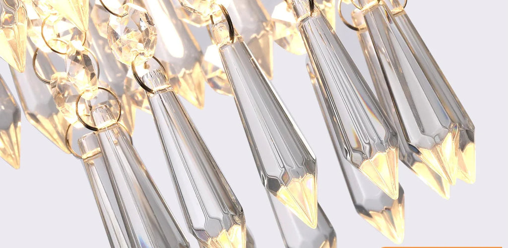 Close-up of the Art Deco chandelier with faceted teardrop glass and gold stainless frame sparkling.