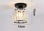 Black-based chandelier with airy suspension, clear cylindrical crystal shade, and warm LED lighting.