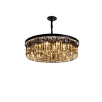Elegant geometric chandelier with vertical crystal prisms on black frame, warmly illuminated with LED lights.