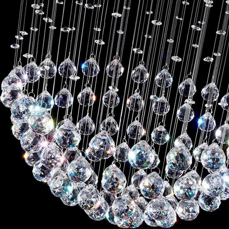 Modern spherical crystal chandelier with glass teardrops and polished steel reflects multicolored LED light.