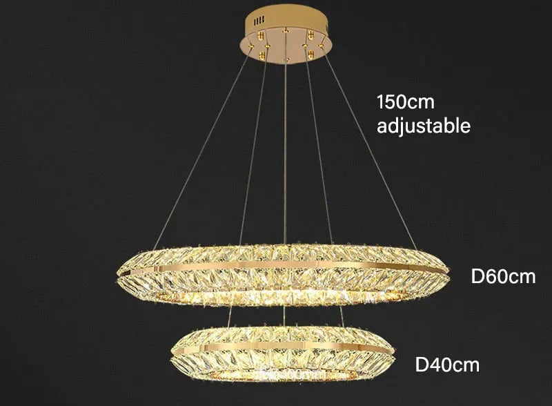 Modern crystal LED chandelier with two gold rings and sparkling crystals, suspended by adjustable wires.