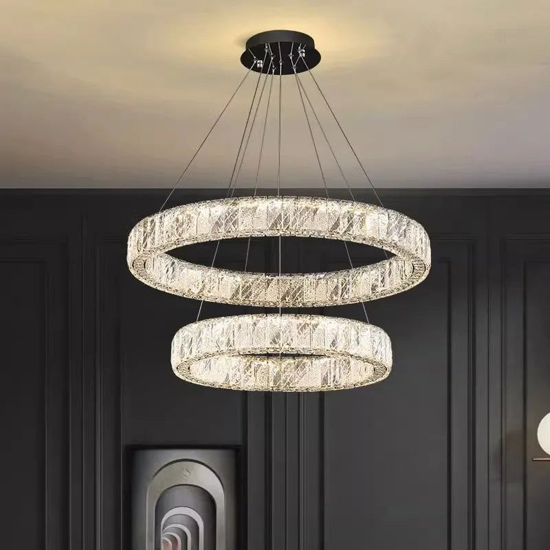 Contemporary chandelier with two illuminated crystal glass rings, suspended at different heights from a black mount.