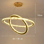 Modern LED chandelier with two intersecting circular crystal rings, gold mount, dimmable, suspended by cables.