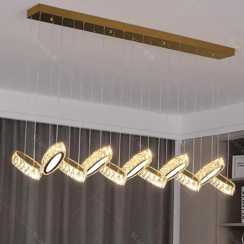 Eight crystal-adorned LED rings on a gold base form a modern, wavy chandelier design.