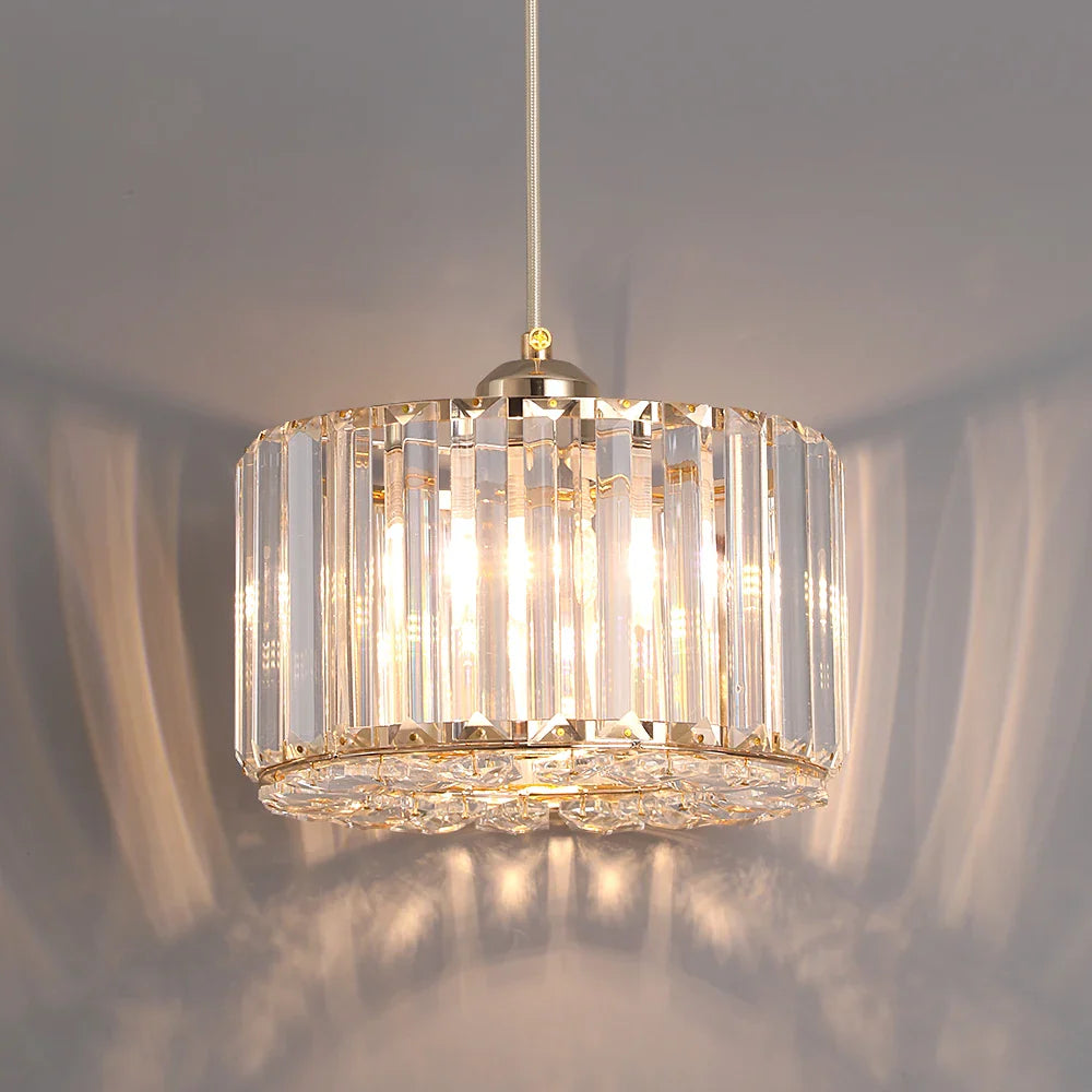 Gold Art Deco chandelier with vertical crystal panels and adjustable rope, warmly illuminating the space.
