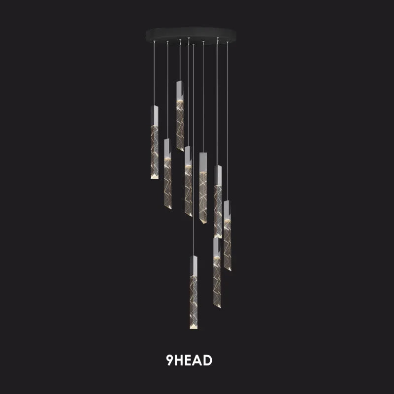 Nine cylindrical pendants with geometric patterns hang at varied lengths from a round black mount.