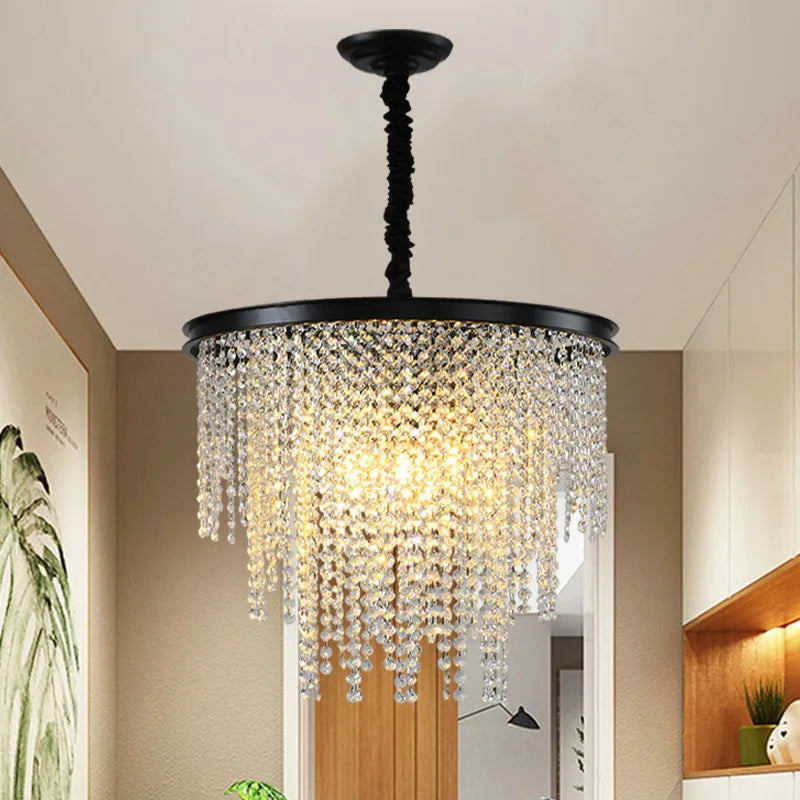 Ornate modern chandelier with clear crystal prisms, gold chain and frame, emits warm light.