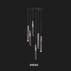 Six cylindrical crystal pendants with geometric patterns hang from a chrome round chandelier frame.