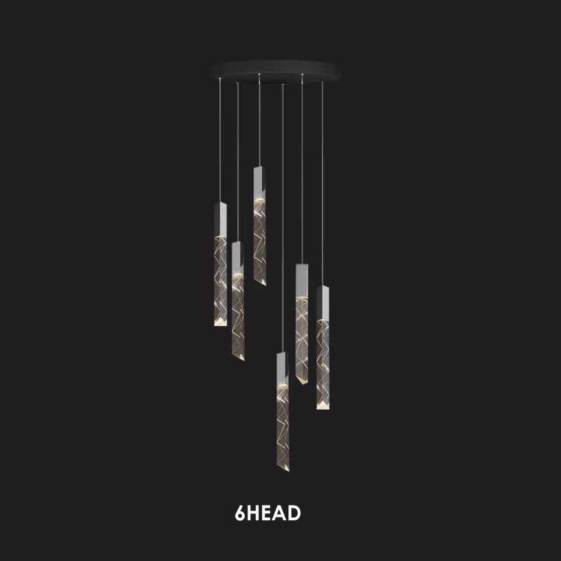 Six cylindrical crystal pendants with geometric patterns hang from a chrome round chandelier frame.
