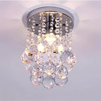 Modern crystal chandelier with chrome base, elegant tassels, and sparkling pendants around glowing bulb.