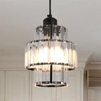 Two-tier chandelier of clear rectangular glass panels with glowing bulb, suspended from a black cord.