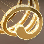 Elegant gold ring chandelier with crystal edges, suspended by wires and warm LED lighting.