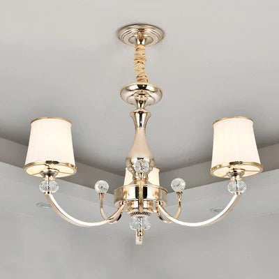 Gold and silver baroque chandelier with three curved arms, white lampshades, and crystal accents.