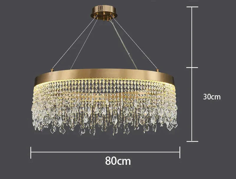 Modern crystal chandelier with gold round frame, hanging crystals, and three suspension wires; 80x30 cm.