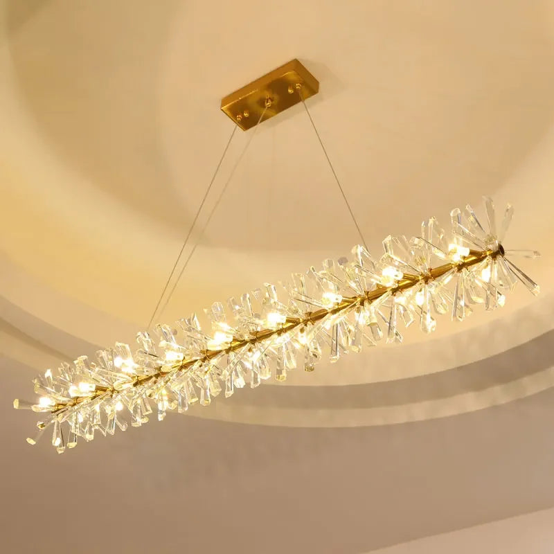 Modern crystal chandelier with hanging LED rings, gold base, and warm yellow glow.