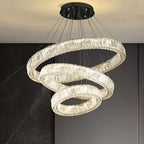 Three illuminated crystal rings intertwine in a pendant chandelier, suspended by thin wires.