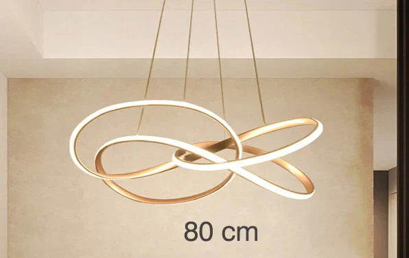 Postmodern crystal chandelier with LED-lit, intertwined gold and white rings suspended by cables.