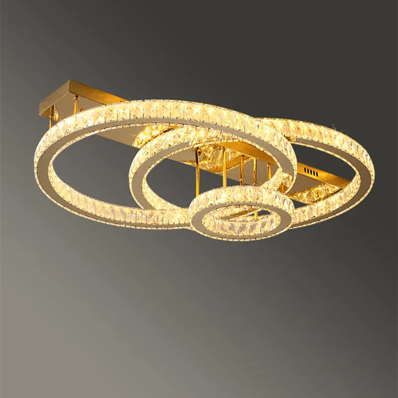 Three intersecting gold rings form a modern chandelier with sparkling crystals and warm LED illumination.