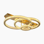 Three interlocking crystal rings form a modern chandelier, suspended from a rectangular gold base.
