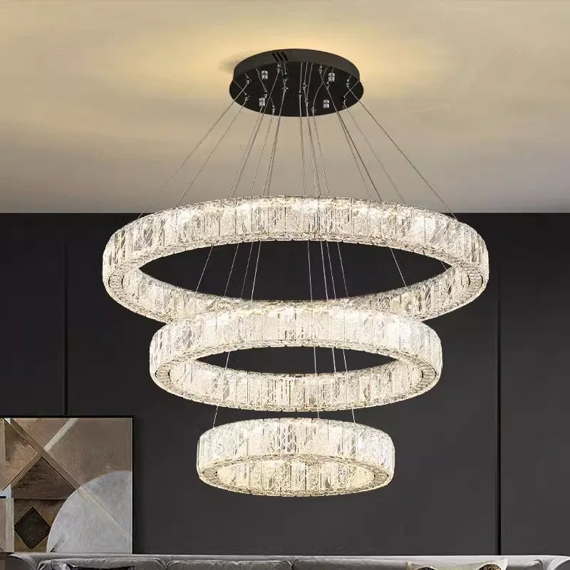 Four crystal rings in graduated sizes, suspended from a black plate, create a modern chandelier.
