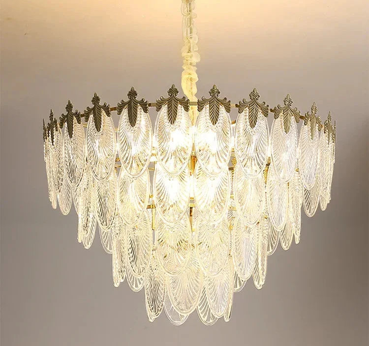 Art Deco chandelier with clear glass leaf tiers and ornate metal, glowing elegantly overhead.