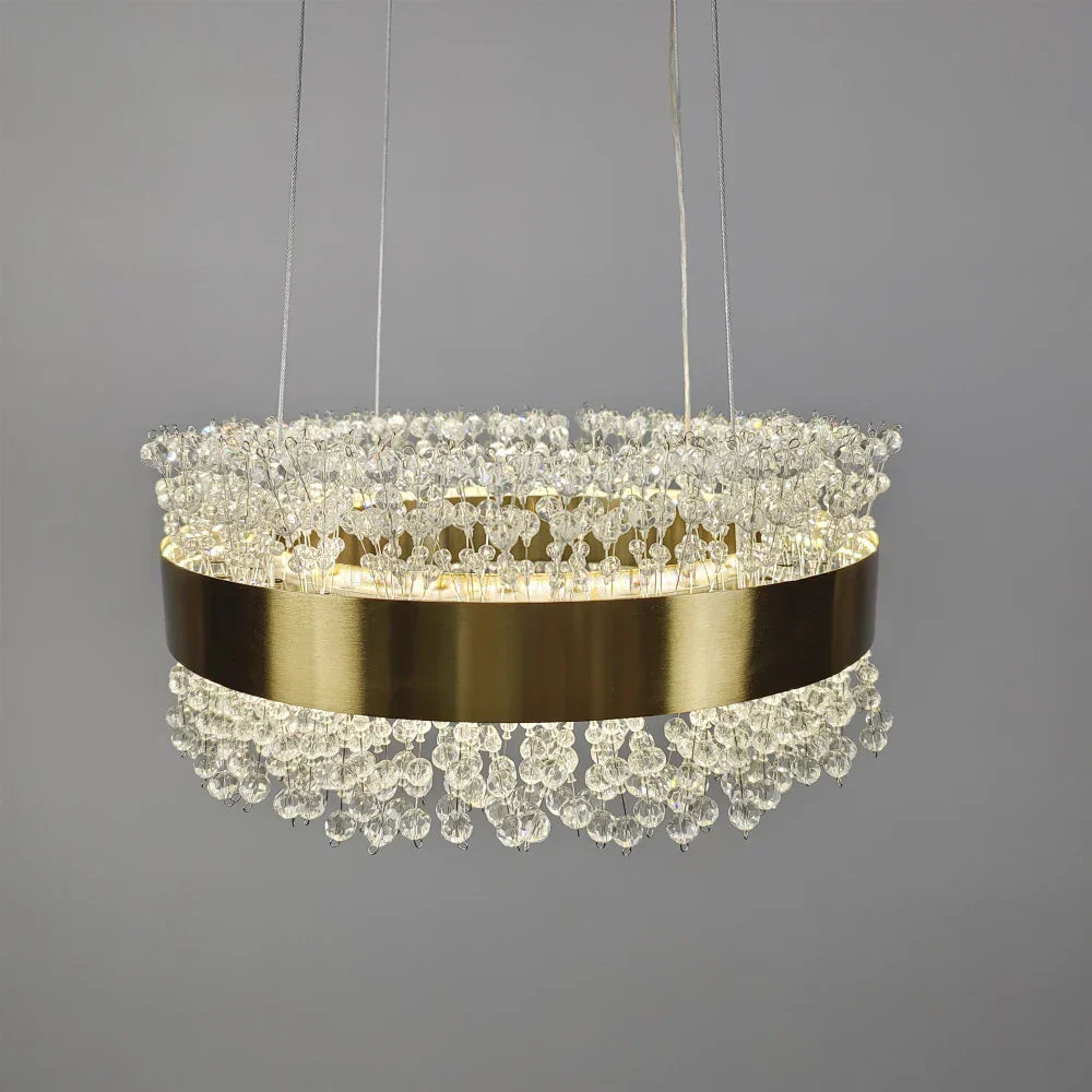 Gold band chandelier with clustered clear crystals, suspended by three thin wires, modern LED design.