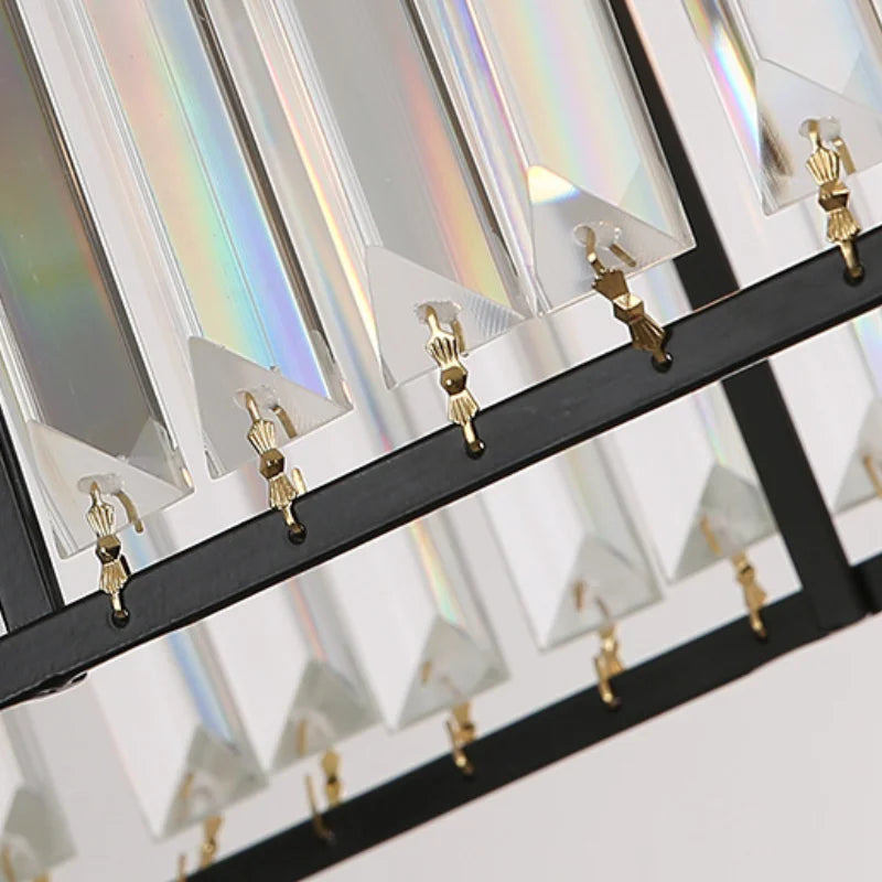Close-up of Maison Ornate Modern Rectangular LED Crystal Chandelier with clear prisms, black frame, and gold hooks reflecting light.