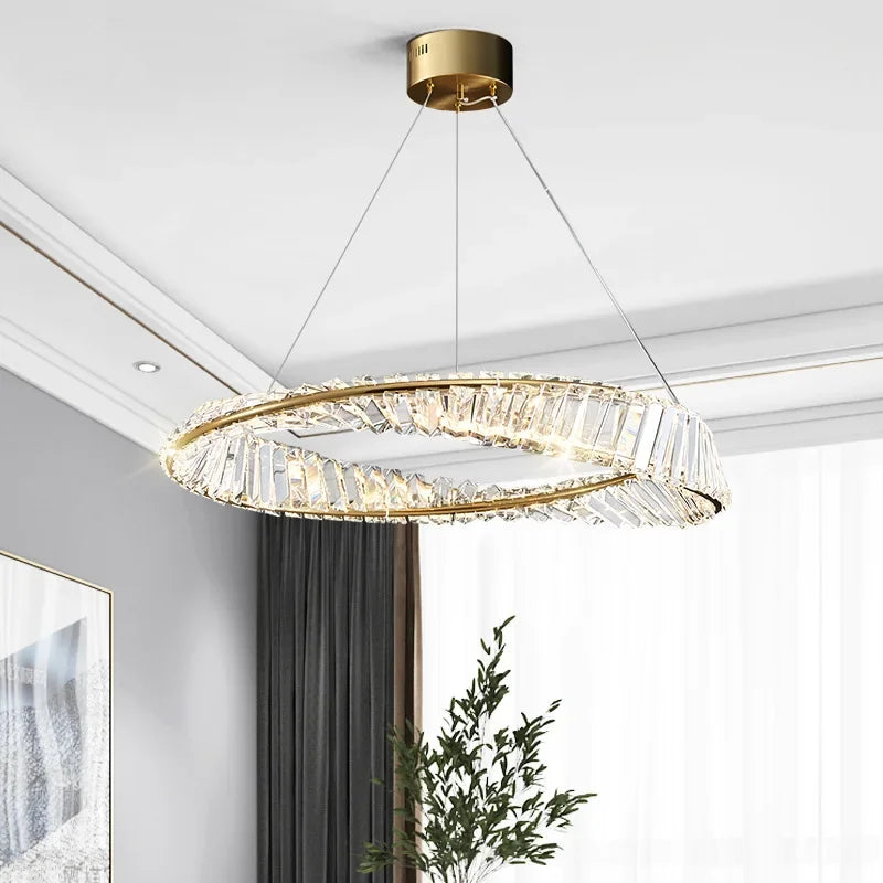 Gold-finished chandelier with spiral oval frame and clear crystal accents, suspended by three cables.