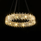 Circular chandelier with ornate golden frame, clear crystal prisms, and multiple warm-hued lights hanging.