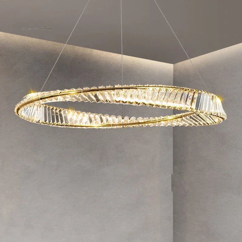 Circular crystal chandelier with twisted design emits a warm golden glow, exuding modern elegance.